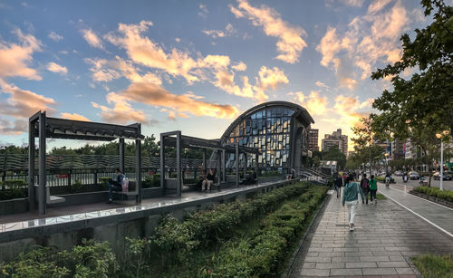 People on bridge against sky during sunset