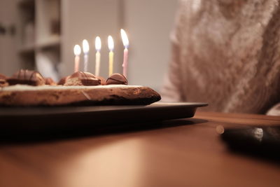 Midsection of person by birthday cake on table