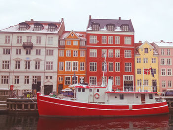 Boats moored in river with buildings in background