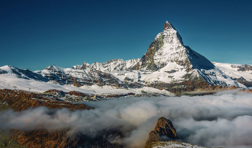 Scenic view of snowcapped mountains against clear blue sky