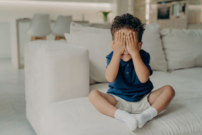 Boy sitting on sofa at home