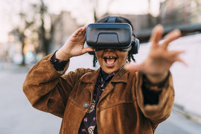 Cheerful woman stretching hand while using virtual reality simulator