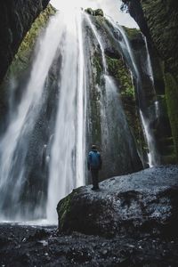 Rear view of man standing against waterfall