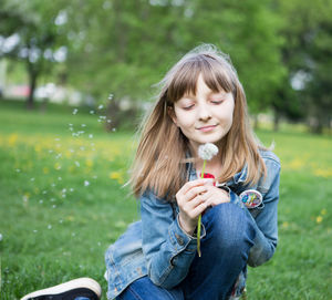 Close-up of a smiling girl holding plant on field