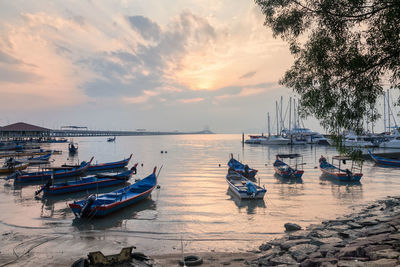 Boats moored on sea against sky during sunset