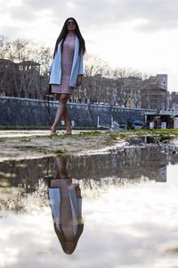 Reflection of woman in puddle at roadside