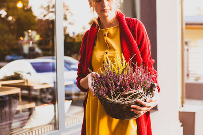 Midsection of woman holding red while standing by railing