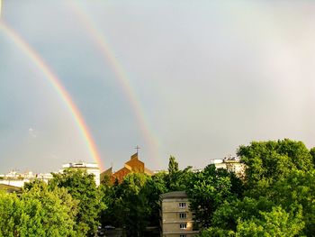 Rainbow over buildings in city against sky