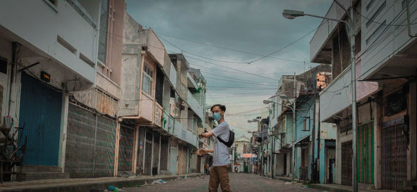 Man standing amidst buildings in city against sky