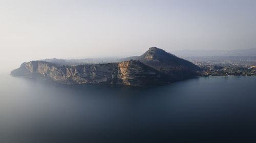 Rock formation in sea against clear sky