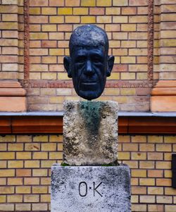 Statue against brick wall