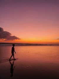 Silhouette man on beach against sky during sunset