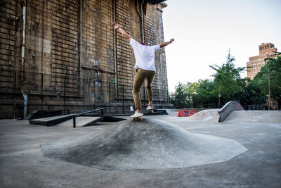 Full length of man skateboarding at skating park against building