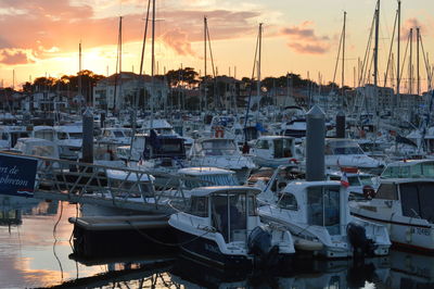 Boats moored at harbor against sky during sunset