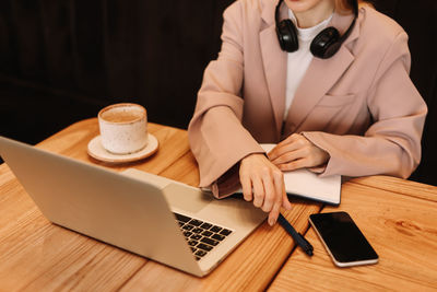 Human hands are typing on a laptop standing on a wooden table. desktop with a coffee mug