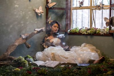 Young woman with artificial butterflies in bedroom