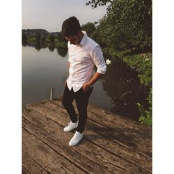 Teenage boy standing on pier over lake