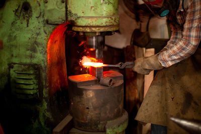 Midsection of blacksmith working at workshop