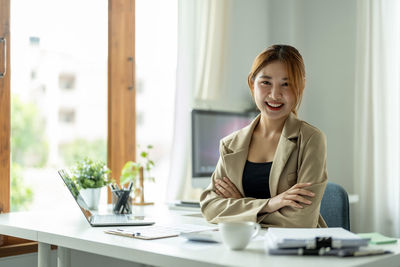 Young woman using laptop while sitting on table