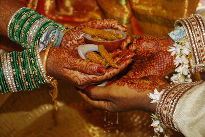 Cropped hand of couple holding food in hand during wedding rituals