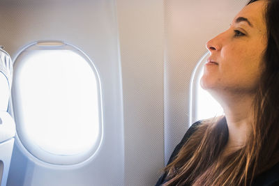 Side view of woman looking through window