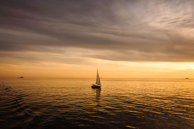 Silhouette sailboat sailing on sea against sky during sunset