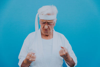 Senior woman doing karate against blue background