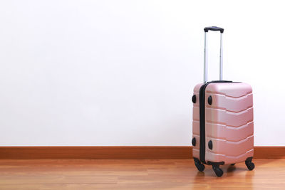 Luggage on hardwood floor against white wall