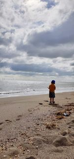 Rear view of man on beach against sky