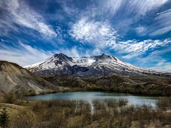 Scenic view of lake by snowcapped mountain against sky