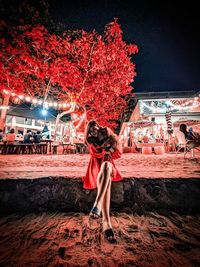 Full length of woman standing against illuminated city at night