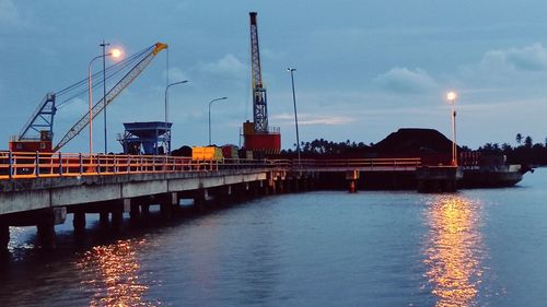 Illuminated bridge over river against sky during sunset