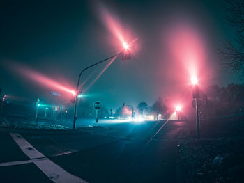 Illuminated street lights against sky at night