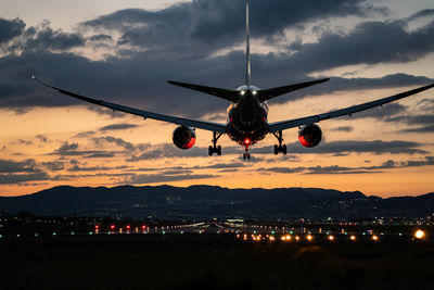 Airplane flying against sky at sunset