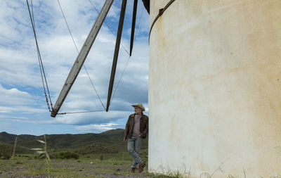 Adult man in cowboy hat standing on field against spanish traditional windmill