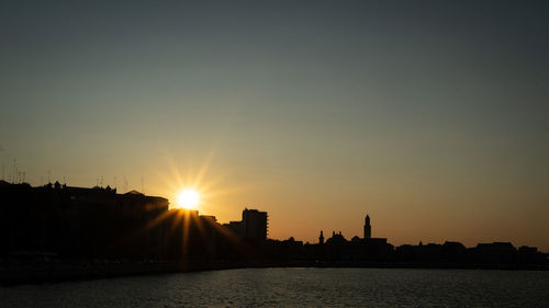 Silhouette buildings against sky during sunset