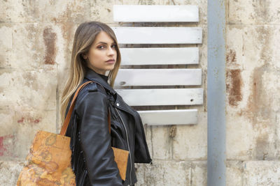 Portrait of beautiful woman standing against wall