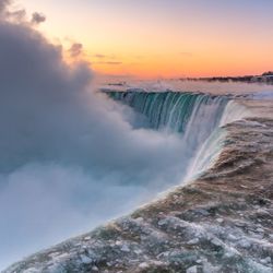 Scenic view of waterfall against sky at sunrise