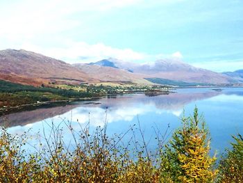 Scenic view of lake by mountains against sky