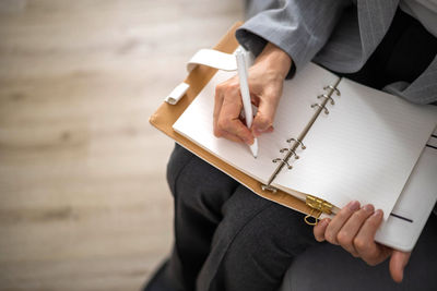 Midsection of man writing in book