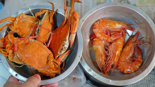 Cropped image of person holding crabs by prawns on table