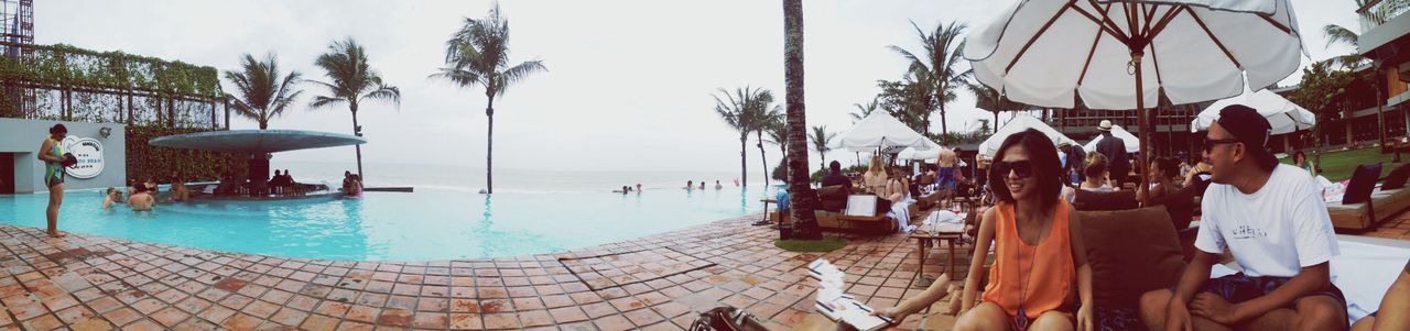 sea, beach, palm tree, water, parasol, sky, horizon over water, tree, beach umbrella, vacations, built structure, swimming pool, sunshade, lounge chair, shore, sand, tourist resort, building exterior, leisure activity