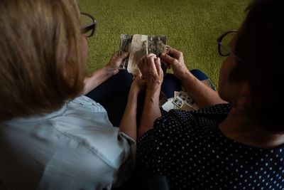 Mature daughter visits senior mother and watching family photo album