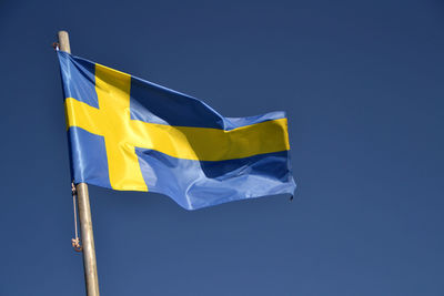 Low angle view of swedish flag against blue sky