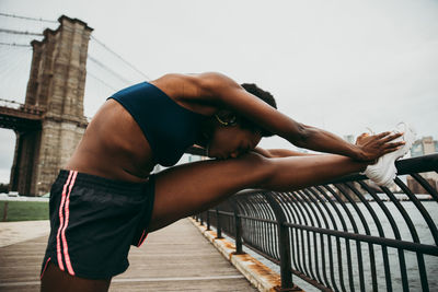 Woman exercising on bridge in city