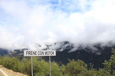 Close-up of road sign against sky