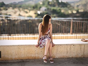 Woman sitting on wall in city