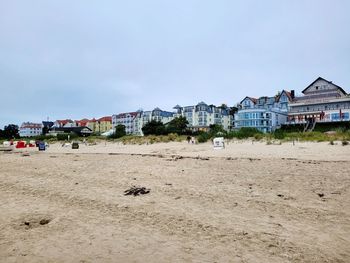 Houses on beach by buildings against sky