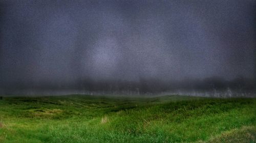 Scenic view of grassy field against cloudy sky