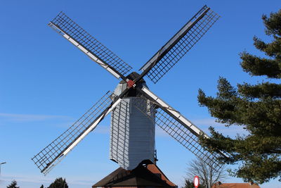 Low angle view of traditional windmill against blue sky